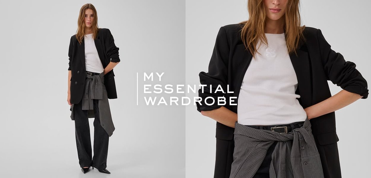 Blazer noir ajusté porté sur un t-shirt blanc, avec un pantalon large sombre doté d'un tissu rayé noué à la taille, mettant en valeur des textures superposées.