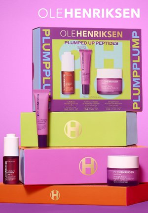 Set di quattro prodotti per la cura della pelle Ole Henriksen. Scatole dai colori vivaci in rosa, verde e arancione. Include flaconi con dettagli bianchi e viola.