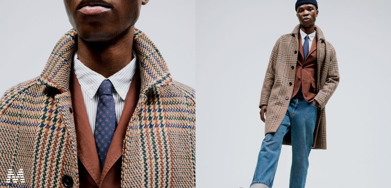 Brown houndstooth wool coat with large buttons, layered over a brown vest and white shirt with blue tie, paired with blue denim trousers.