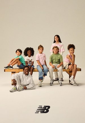 Zes kinderen en een tiener in informele kleding en sneakers zitten en poseren op en rond een houten bank tegen een eenvoudige achtergrond met het New Balance-logo.