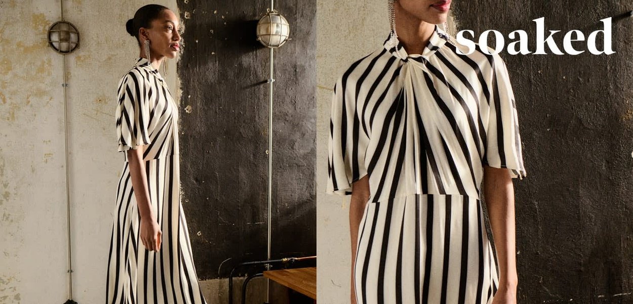 Striped dress in black and white, featuring a collar, short sleeves, and a loose fit. Smooth fabric with a vertical stripe pattern.