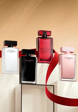 Vier parfumflesjes: helder wit, zwart, rood en roze glas met zwarte vierkante doppen. Een rode lint is artistiek om de display gerangschikt.