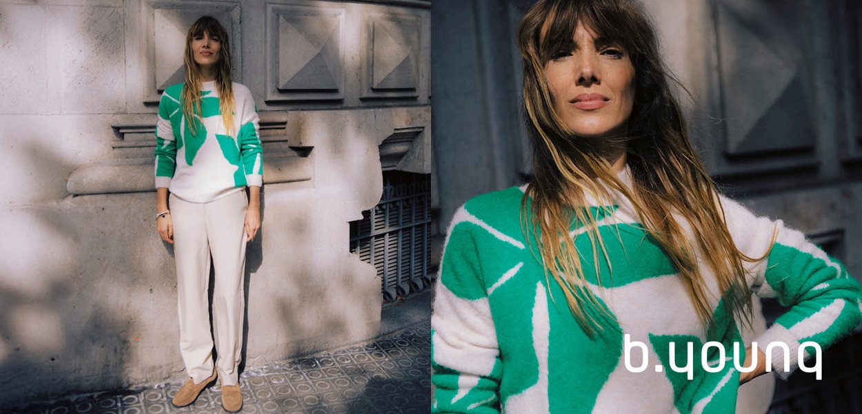 Weißer Pullover mit grünen Blattmustern, kombiniert mit hellbeigen Hosen. Weiche Textur, lässige Passform und minimalistische Designdetails.