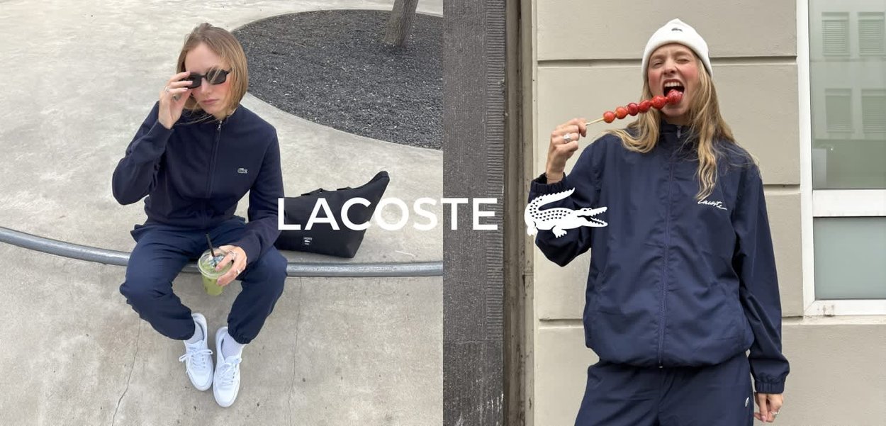 Marineblauw trainingspak van gladde stof, met een volledig ritssluiting jack met logo, gecombineerd met witte sneakers en accessoires.