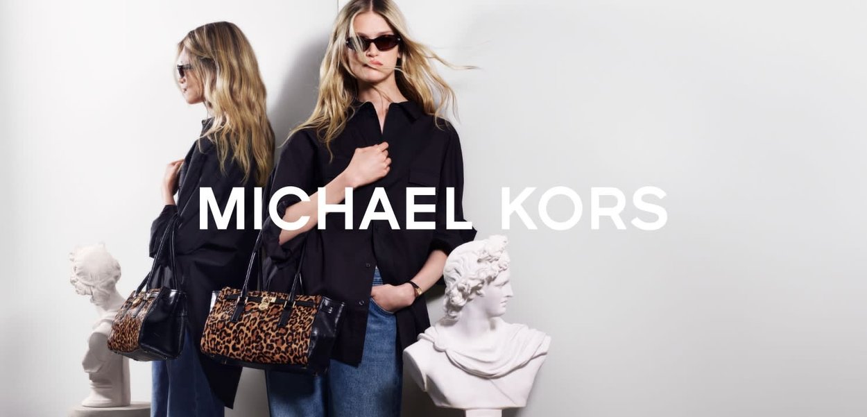 Zwart en bruin handtas met luipaardprint en gestructureerde vorm, vastgehouden door een model dat een zwart shirt en donkere zonnebril draagt, tegen een lichte achtergrond.