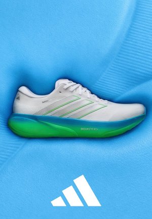 Biały but do biegania Adidas z zielonymi akcentami i zieloną podeszwą na niebieskim, teksturowanym tle z logo Adidas.