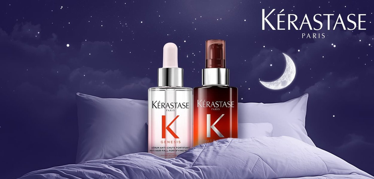 Two Kérastase Paris hair serum bottles on a bed with pillows under a starry night sky and crescent moon.