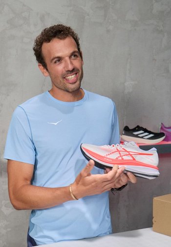 Leichte Laufschuhe in Grau und Pink, mit einem strukturierten Mesh-Obermaterial, gepolstertem Kragen und kontrastierender Außensohle. Sichtbares Markenlogo.