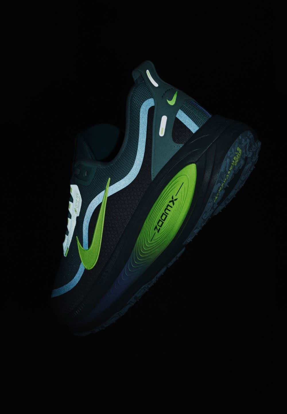 Sneaker Nike avec un dessus en maille noire, des accents verts et bleus, une forme courbée, une semelle texturée et un amorti Air Zoom visible.