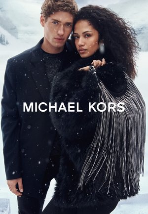 Płaszcz z futerkiem z imitacji od Michaela Korsa z frędzlami, w połączeniu z czarnym strojem. Ośnieżone, zewnętrzne otoczenie podkreśla fakturę i detale projektu.