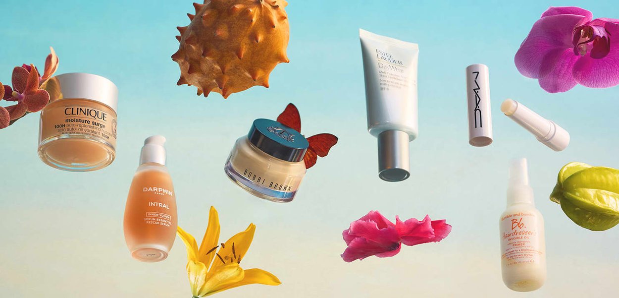 Productos de cuidado de la piel y maquillaje de Clinique, Darphin, Bobbi Brown, Estée Lauder, MAC y Bumble and bumble flotando junto con flores y frutas coloridas.