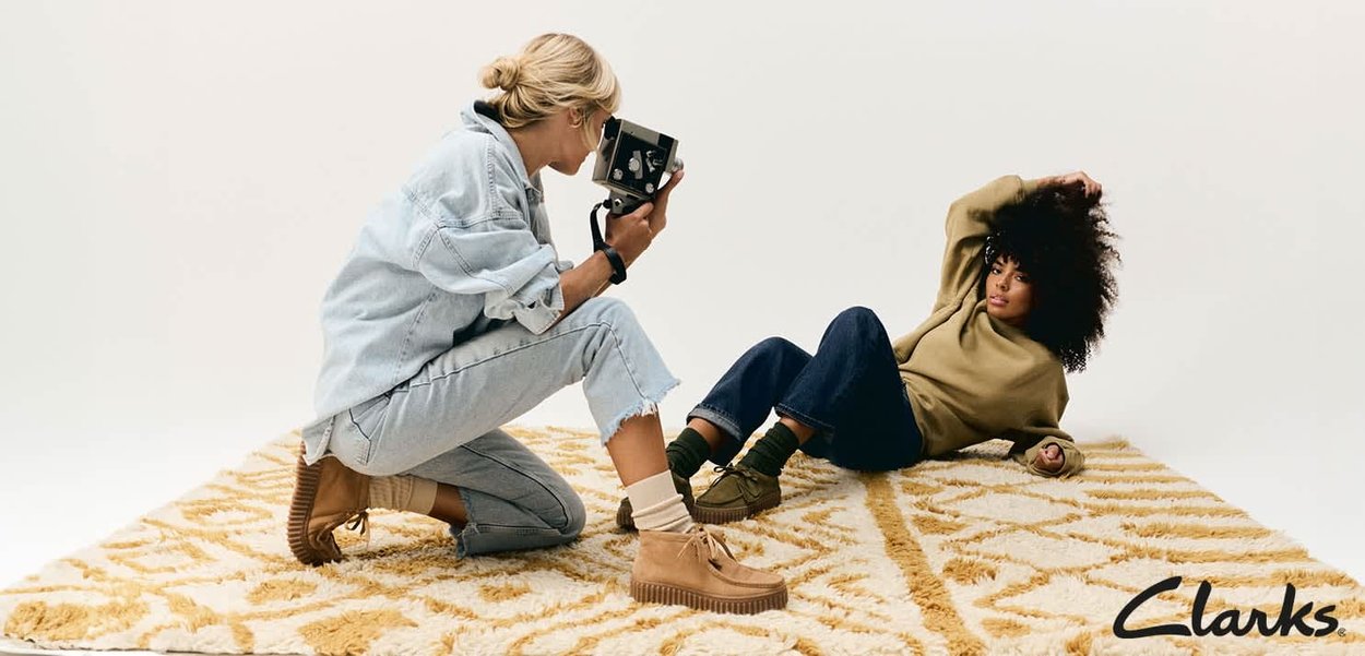 Bottes en Daim beige avec une semelle épaisse en caoutchouc. Tenue décontractée en denim et un sweat-shirt vert porté par un mannequin. Séance photo sur un tapis texturé.