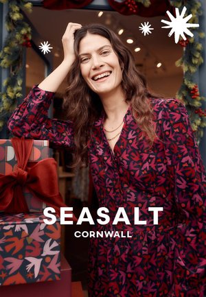 Dunkelrosa Kleid mit Blumenmuster, langen Ärmeln, Knopfdetails und lockerem Sitz, daneben Geschenkboxen mit aufwendigen roten und blauen Mustern.