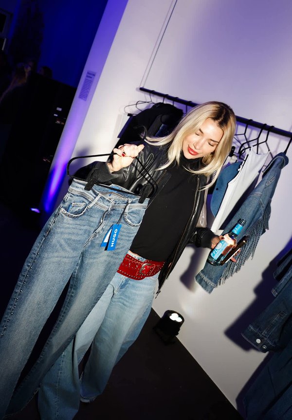 Light blue denim jeans with a straight cut, wide legs, and studded accents. Black leather jacket worn over a black top, red belt, and accessories.