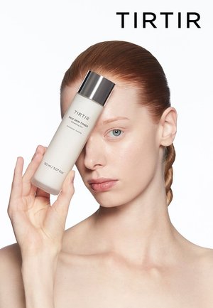 TIRTIR Milk Skin Toner in a frosted bottle with a silver cap, held against a pale background. The product is 150 ml, labeled for hydration.