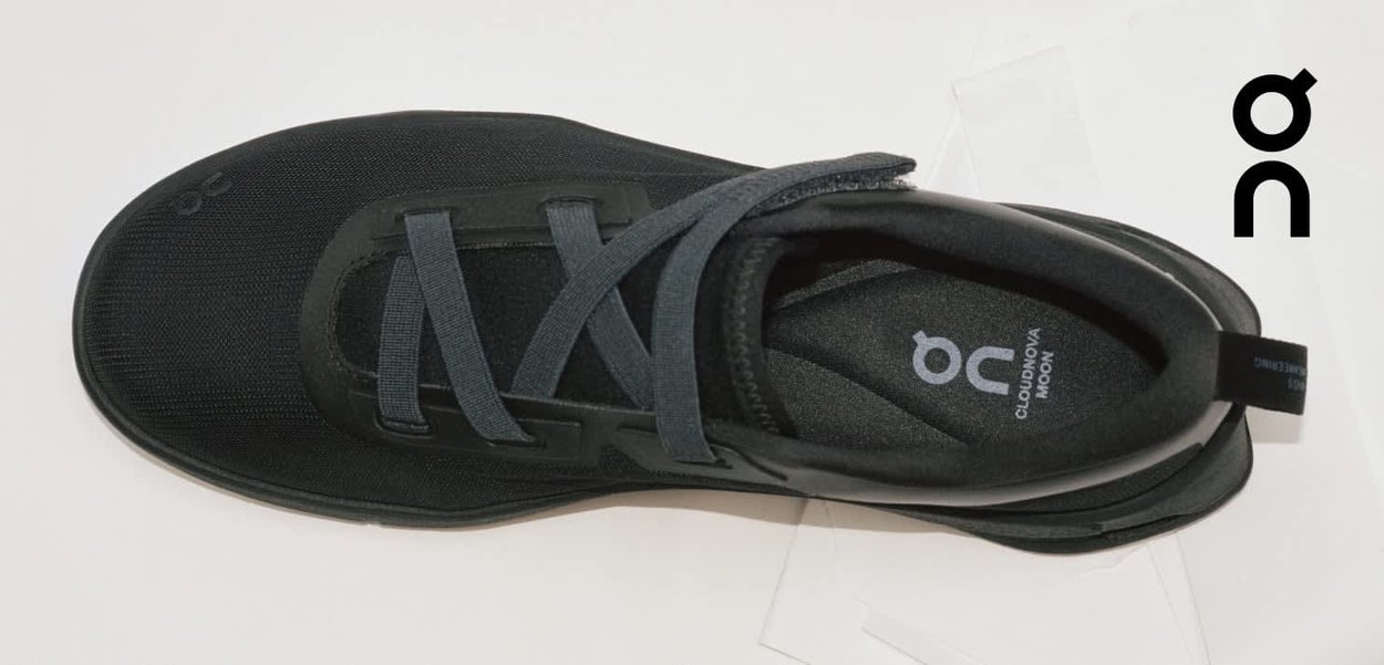 Zapatilla negra On Cloudnova Moon con cordones oscuros, interior acolchado y logo visible en la plantilla y en la esquina superior derecha.