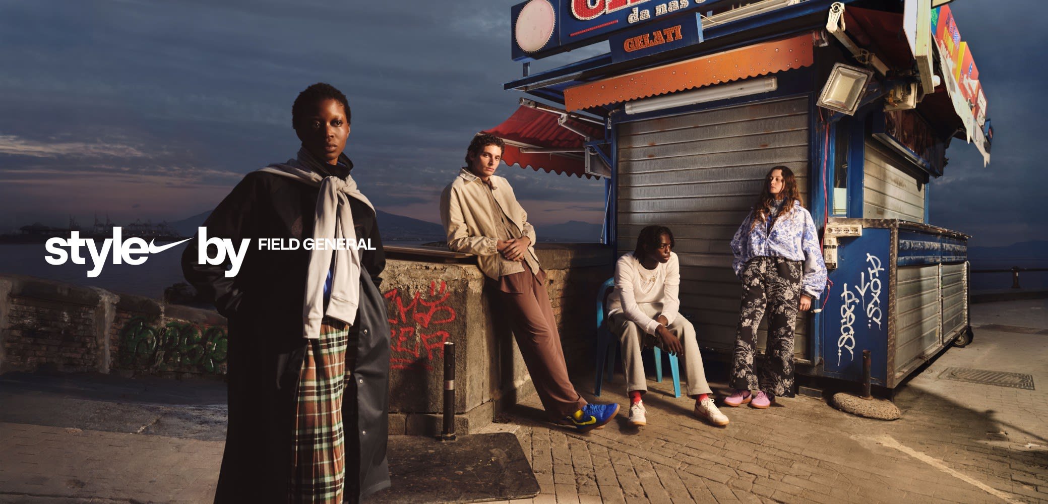 Quattro individui posano in stile urbano. Texture, colori e fantasie variegate: un cappotto nero, un giubbotto beige, pantaloni stampati e sneakers colorate.