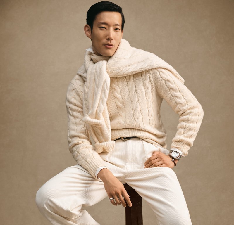 Kermaviinin värinen palmikkoneulepusero, johon on yhdistetty samanlainen huivi, ja valkoiset ribbihousut. Huomionarvoisia yksityiskohtia ovat rannekello ja vyö.