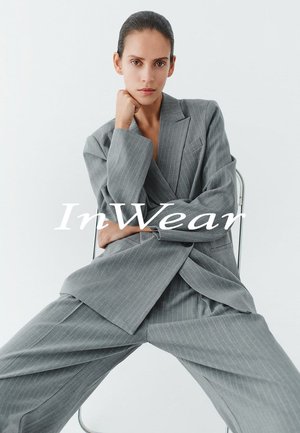 Grau gestreifter Anzug mit entspannter Passform, bestehend aus einem zweireihigen Blazer und lockeren Hosen. Glatter Stoff und klare Linien.