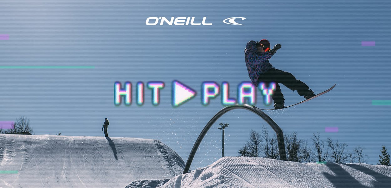 Snowboarder in der Luft über einem gebogenen Geländer an einem schneebedeckten Hang mit klarem blauem Himmel und O'Neill-Logo darüber.