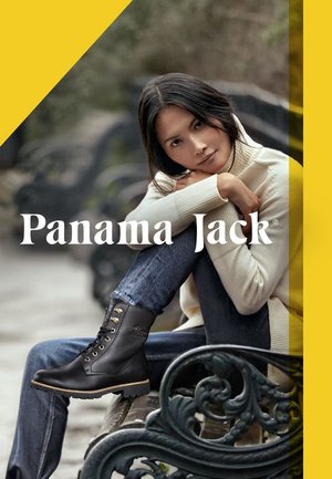 Zwarte leren laarzen met gouden hardware, een gestructureerde afwerking en een robuuste zool, gecombineerd met jeans en een crèmekleurige trui, tegen een vervaagde achtergrond.