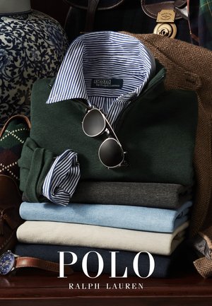 Assortimento di maglioni piegati in vari colori: verde scuro, azzurro, grigio, blu navy. Include una camicia con colletto a righe blu e bianche e occhiali da sole.