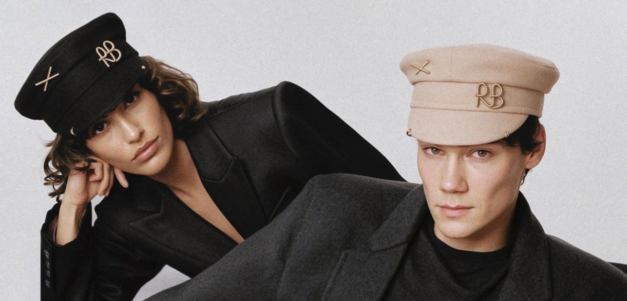 Vier Personen tragen verschiedene Mützen: eine beige, eine marineblaue, eine grüne und eine schwarze, jeweils mit einzigartigen Verzierungen, dazu dunkle Mäntel.