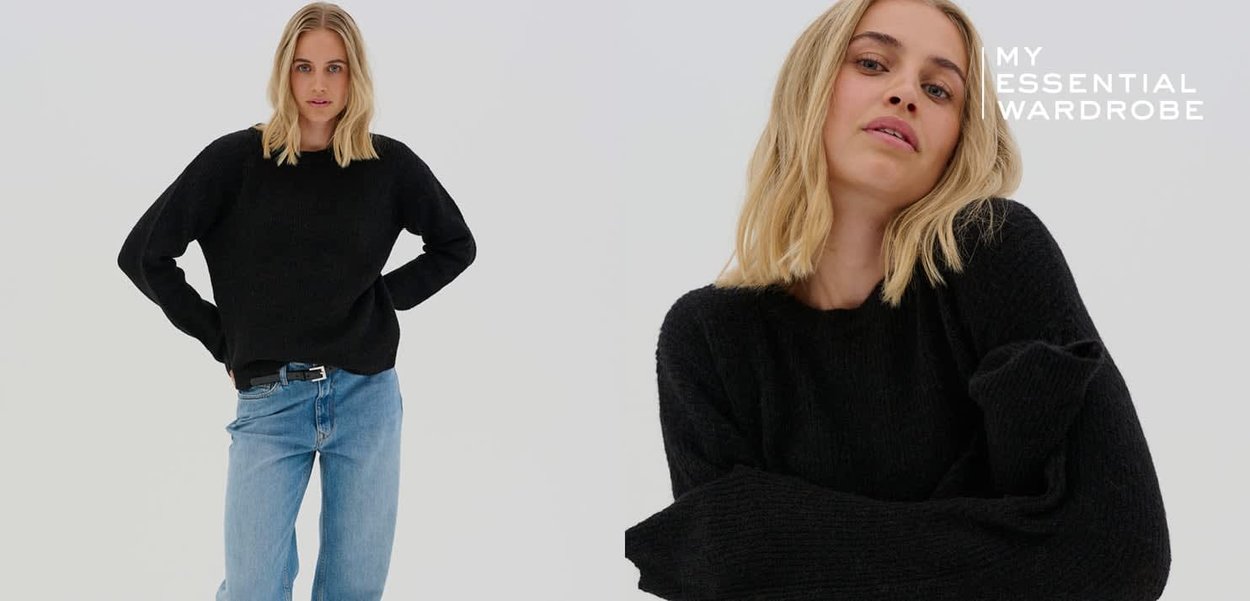 Schwarzer Strickpullover mit lockerem Schnitt, Rundhals und angesetzten Schultern, kombiniert mit hellblauen Jeans. Weiche Textur und lässiges Design.