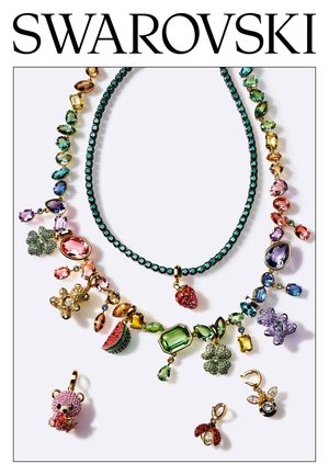 Kettingen en kleurrijke kristallen bedeltjes in vormen zoals beer, bloem, aardbei en lieveheersbeestje met Swarovski-logo erboven op een witte achtergrond.