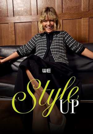 Lachende vrouw met blond haar zit op een zwarte leren sofa en draagt een zwart-wit gebreid vest en een zwarte rok, tegen een houten paneelmuur.