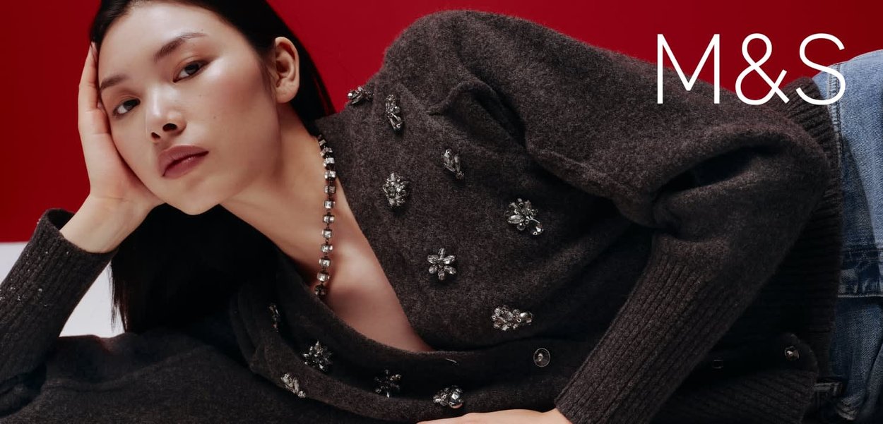 Cardigan brun foncé en maille texturée, orné d'applications florales argentées et de boutons décoratifs, associé à un jean en denim.