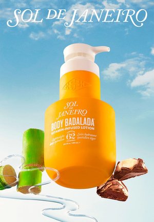 Helderoranje fles van Sol de Janeiro Body Badalada vitamine-rijke lotion met ingrediënten van suikerriet en noten tegen een blauwe lucht.