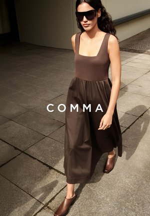 Woman wearing sleeveless brown dress, large dark sunglasses, and brown shoes walking on tiled pavement with shadow visible.