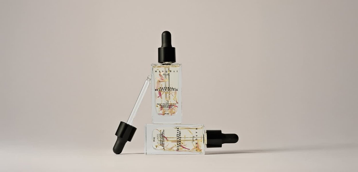 Des bouteilles compte-gouttes en verre transparent avec des couvercles noirs, contenant un liquide avec des accents floraux. Trois bouteilles disposées en triangle, de 50 ml chacune.