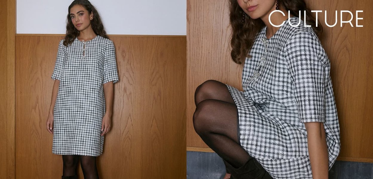 Vestito a quadri in bianco e nero, con maniche corte e vestibilità ampia. Dettagli notevoli includono un'apertura con bottoni e una silhouette rilassata.