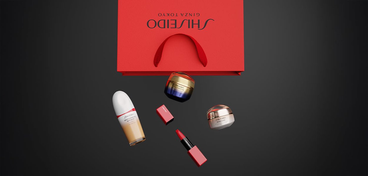 Rød Shiseido gaveæske med udskårne håndtag, indeholdende en cremeflaske, to krukker, en læbestift og en lille rød kompakt. Blank og med metal-detaljer.