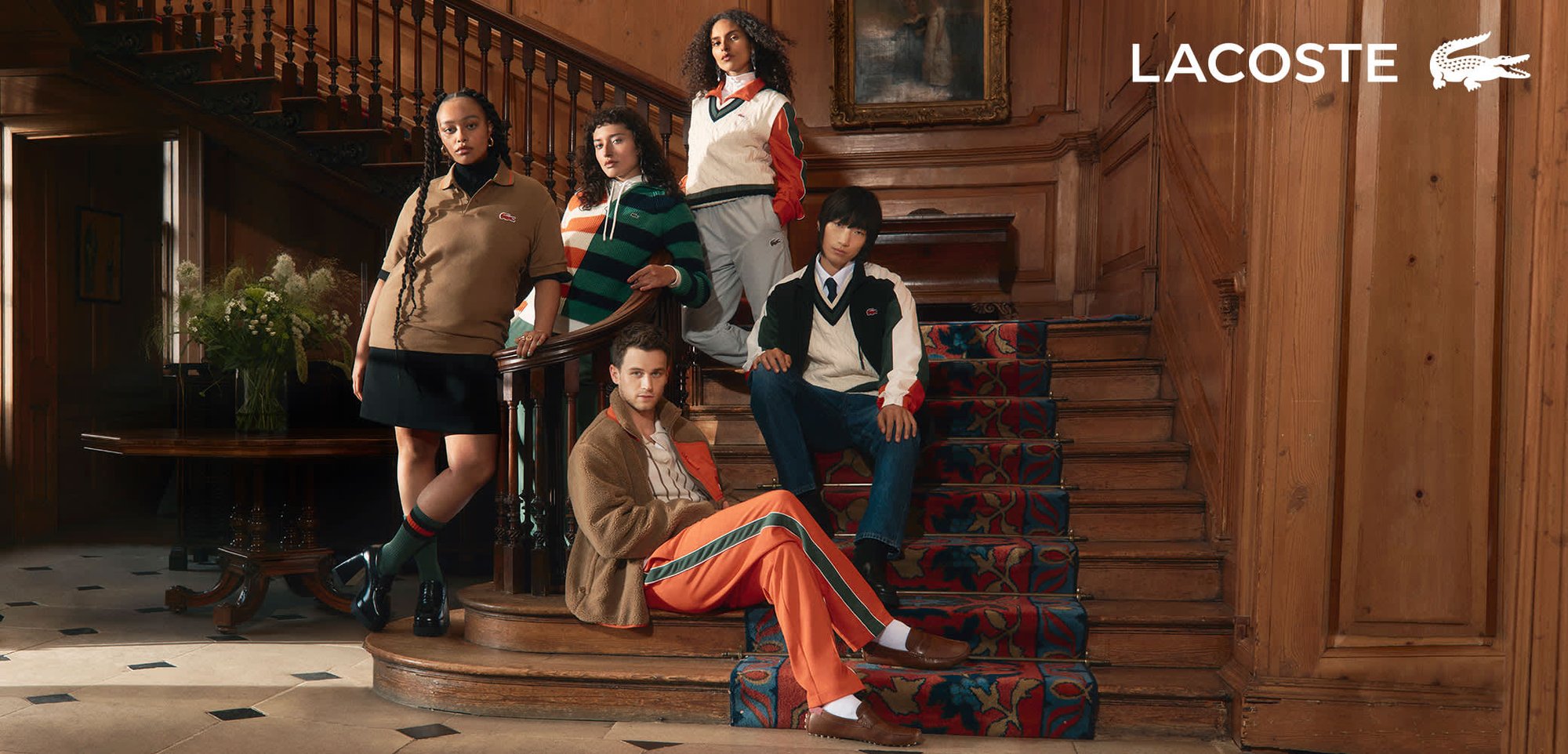Des vêtements Lacoste présentés sur cinq personnes : polo brun, tricot rayé, sweat-shirt blanc, veste marron, survêtement orange, avec des textures et motifs variés.