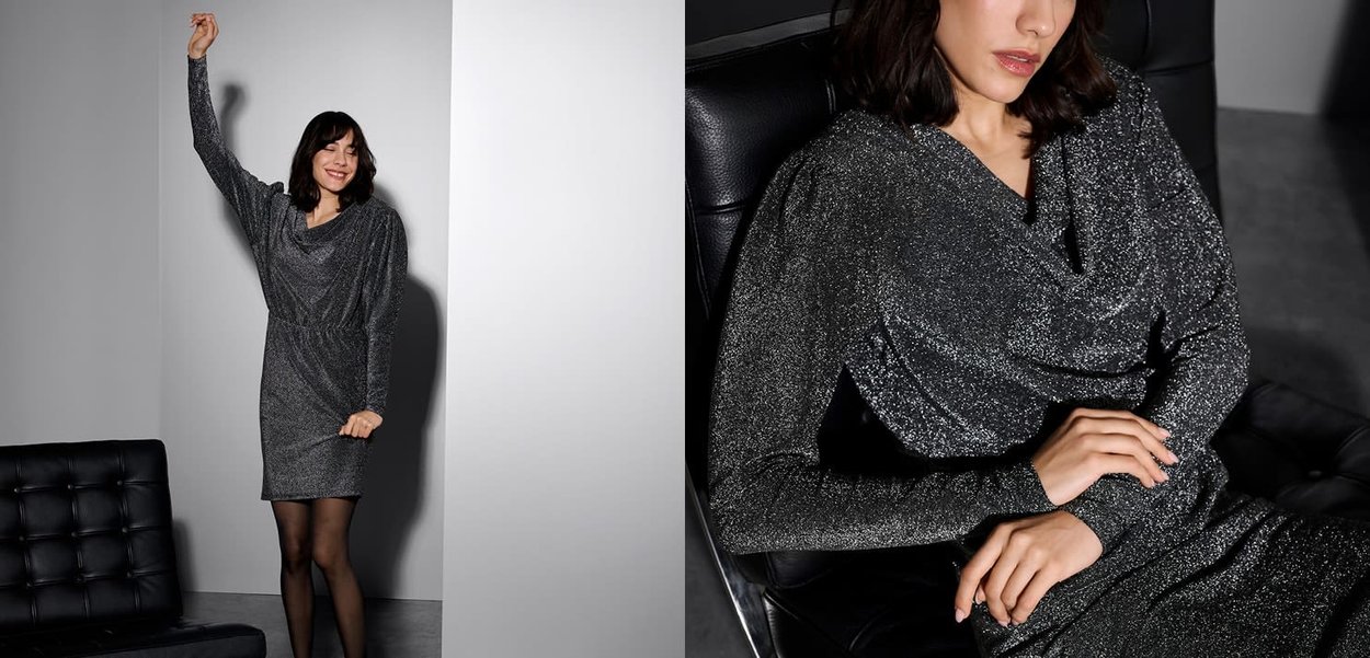 Funkelndes schwarzes Kleid mit einem drapierten Ausschnitt, langen Ärmeln und einer figurbetonten Silhouette. Strukturierter Stoff schimmert im Licht.