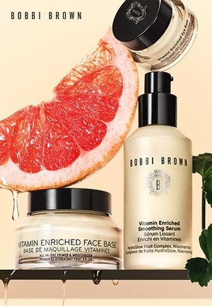 Trois produits de soin de la peau Bobbi Brown : un pot de Base Enrichie en Vitamine, une bouteille de Sérum Lissant et une tranche de pamplemousse.