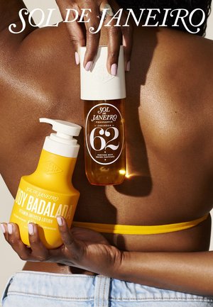 Person with dark skin and pale nail polish holds Sol de Janeiro fragrance mist and yellow body lotion against bare back, wearing yellow bikini and jeans.