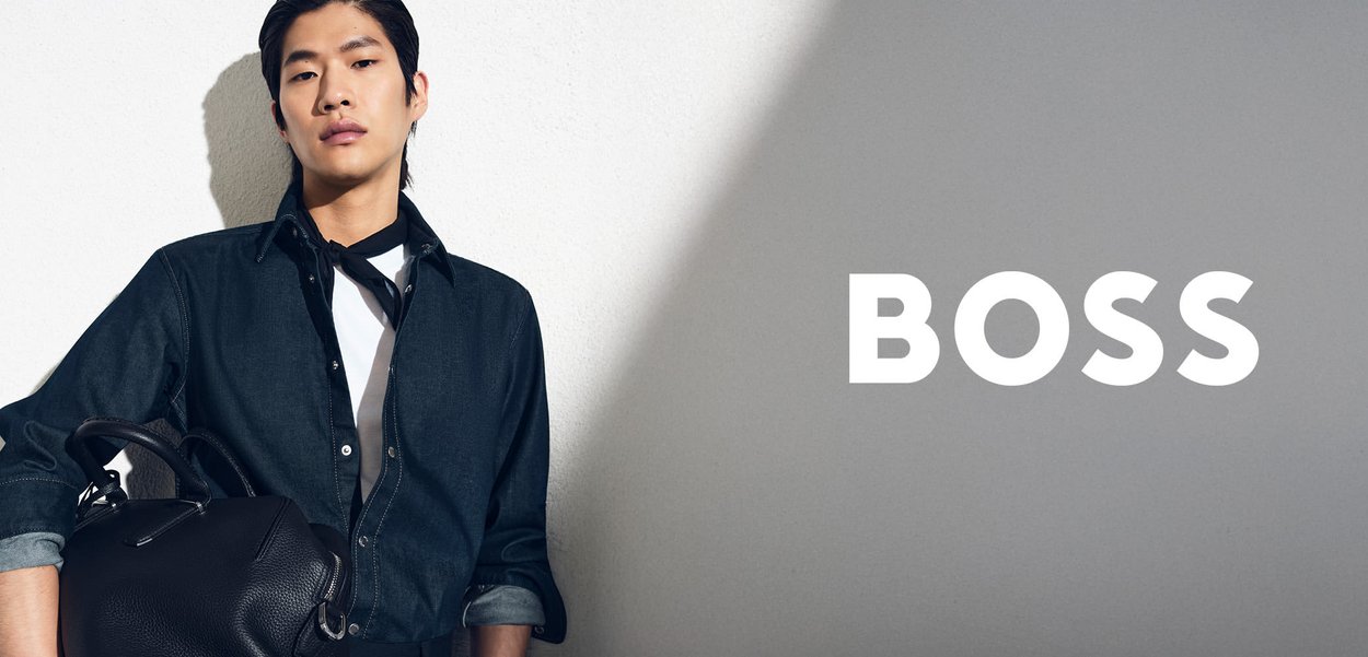 Hellbraunes, langärmeliges Poloshirt mit dezenter Logo-Applikation, kombiniert mit beigen Hosen. Der Stoff wirkt glatt, verfügt über einen legeren Schnitt und einen natürlichen Glanz.