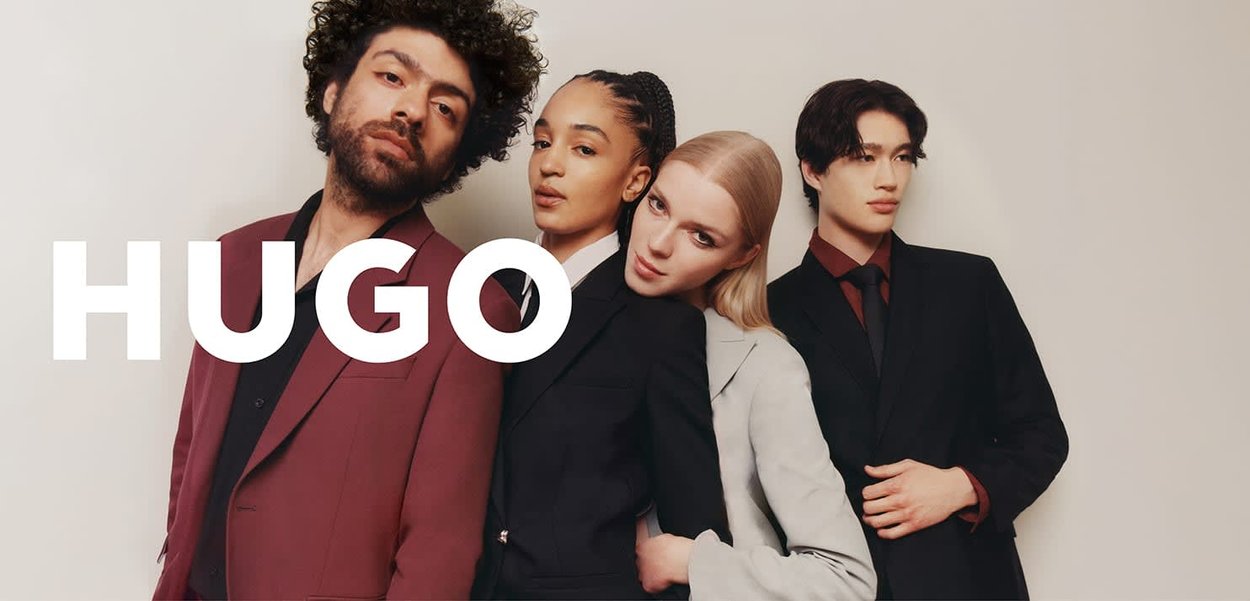 Quatre personnes en tenue formelle : un costume bordeaux, un costume gris clair, un costume foncé avec une chemise bordeaux, et un costume noir. Fond neutre.