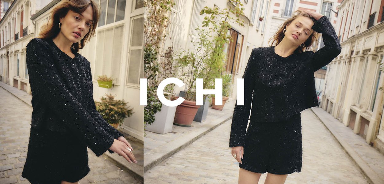 Schwarzer, strukturierter Zweiteiler bestehend aus einem cropped Pullover mit langen Ärmeln und passenden Shorts, vor einem Kopfsteinpflasterweg.