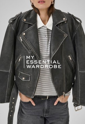 Black leather motorcycle jacket with multiple zippered pockets, silver hardware, and shoulder epaulettes, layered over a striped shirt.
