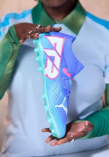 Blaue und lila Fußballschuhe mit einem strukturierten Mesh-Obermaterial, türkisfarbener Sohle und auffälligem weißen Logo. Verfügt über ein eng anliegendes Design für Agilität.
