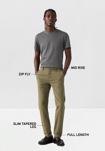 Camiseta gris de manga corta combinada con pantalones ajustados de talle medio en verde oliva, de corte estrecho y acabado cónico, con cremallera, de largo completo y usados con zapatos oscuros.