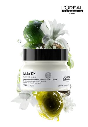 Masque en pot L’Oréal Professionnel Metal DX avec des fleurs blanches, du citron vert et des gouttes de gel transparent sur un fond blanc.
