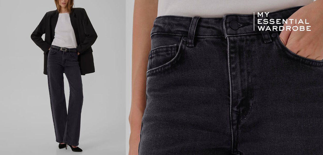 High-Waist, dunkelgraue Denim-Flaired Jeans mit Knopfverschluss, fünf Taschen und dezenten Used-Details, kombiniert mit einem weißen Oberteil und Blazer.