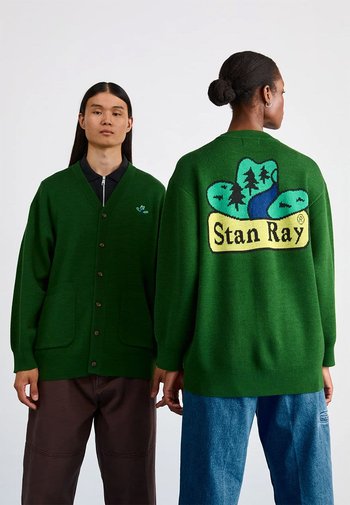 Groene gebreide cardigan met een knoopsluiting aan de voorkant, lange mouwen, twee voorzakken en een grote grafiek op de rug met bomen, een rivier en de tekst "Stan Ray."