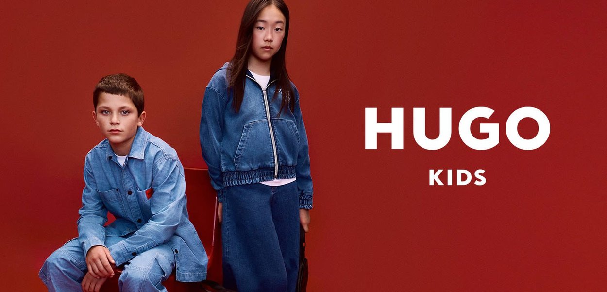 Denim jacket and skirt set in light blue, featuring a zip front and elastic waistband, displayed against a red background. "HUGO KIDS" text included.